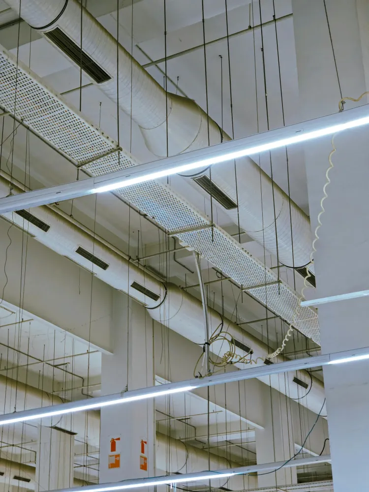 Large suspended ductwork and ceiling components inside a commercial building with bright overhead lighting. The image reflects HVAC System Inspections and Maintenance in a commercial interior.